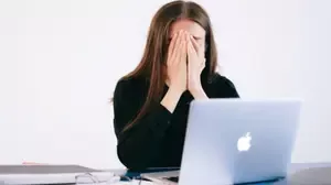 Woman covering her face while sitting at a laptop, illustrating emotional overwhelm and the need for effective BPD therapy.