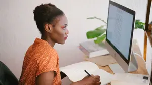 Social worker studying online and taking notes as part of a continuing education program to develop new career skills and advance professionally.