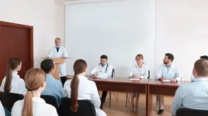 Group of healthcare executives in a small-room meeting listening to speakers during an executive healthcare conference focused on collaboration and strategy.