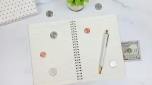 Notebook, pen, coins, and cash on a desk, illustrating financial self-control and better money habits.