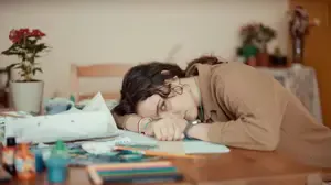Person resting at a cluttered table, illustrating autistic inertia, task paralysis, and difficulty moving from intention into action.