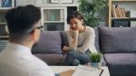 A woman in a therapy session expressing emotional distress, seated across from a mental health professional - representing EMDR therapy in practice.