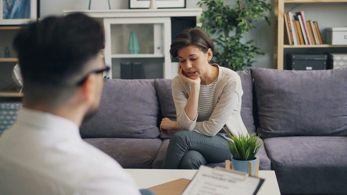 A woman in a therapy session expressing emotional distress, seated across from a mental health professional - representing EMDR therapy in practice.