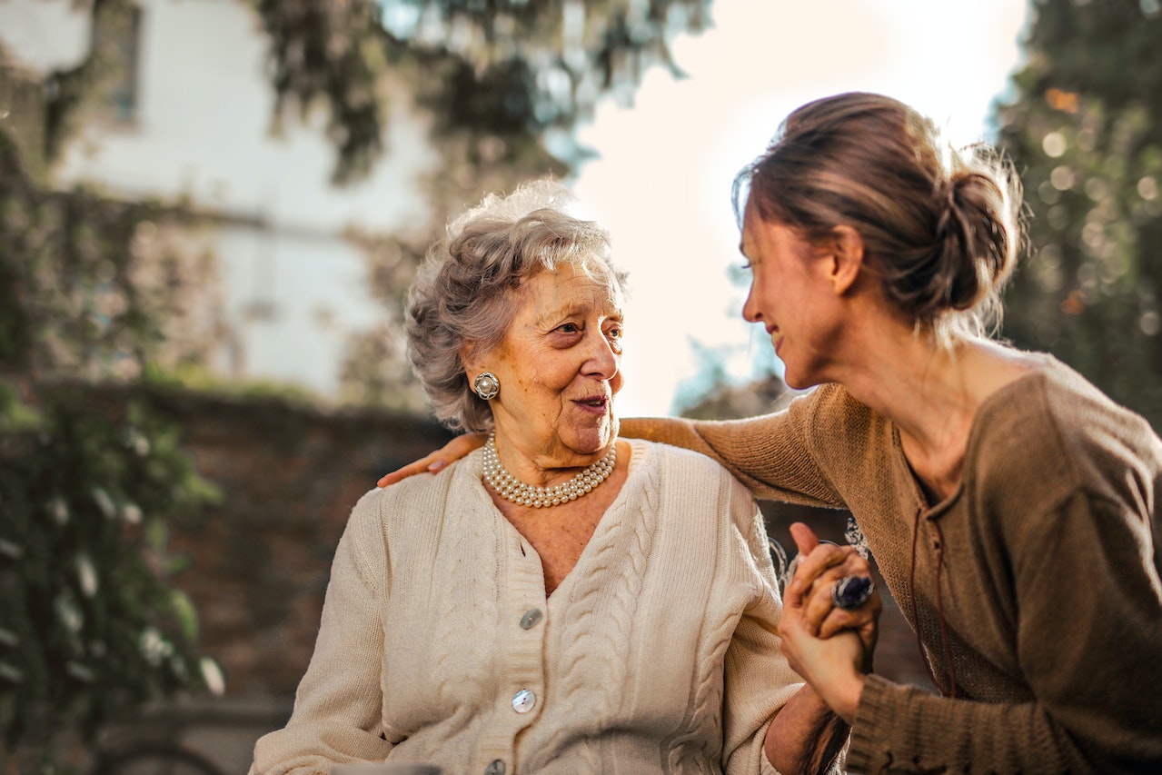 Joyful adult daughter greeting happy senior mother in garden