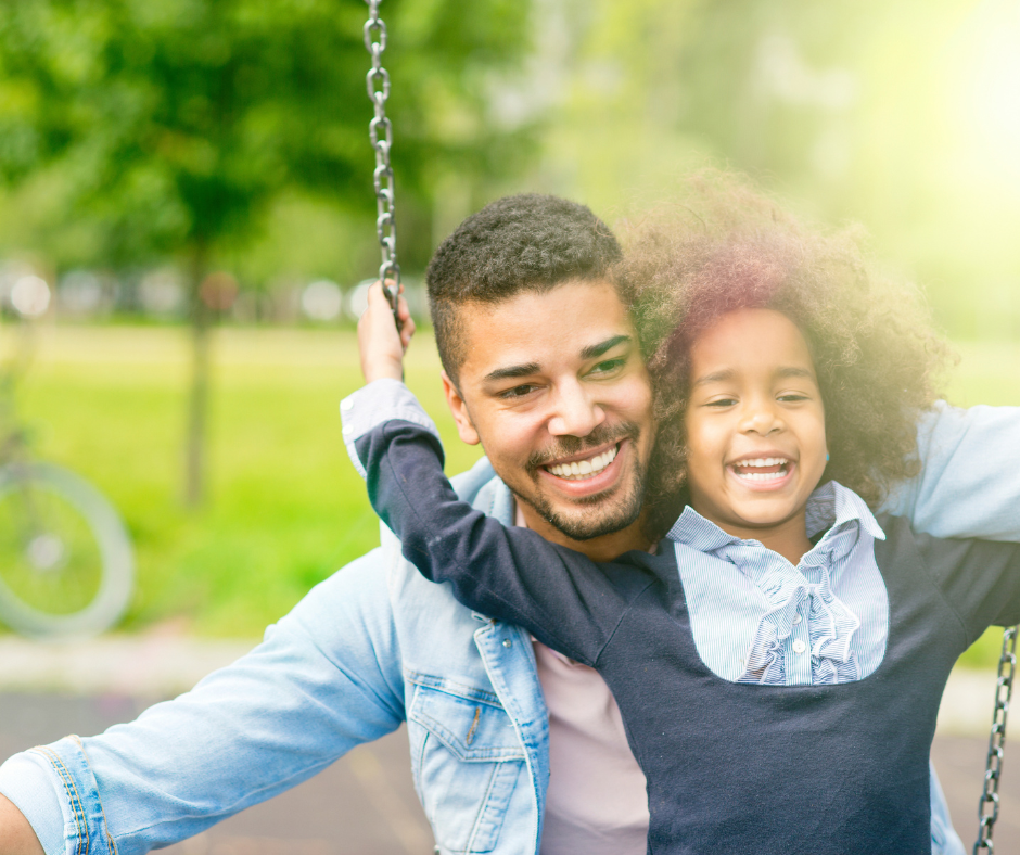 Father and daughter playing on a swing in the park