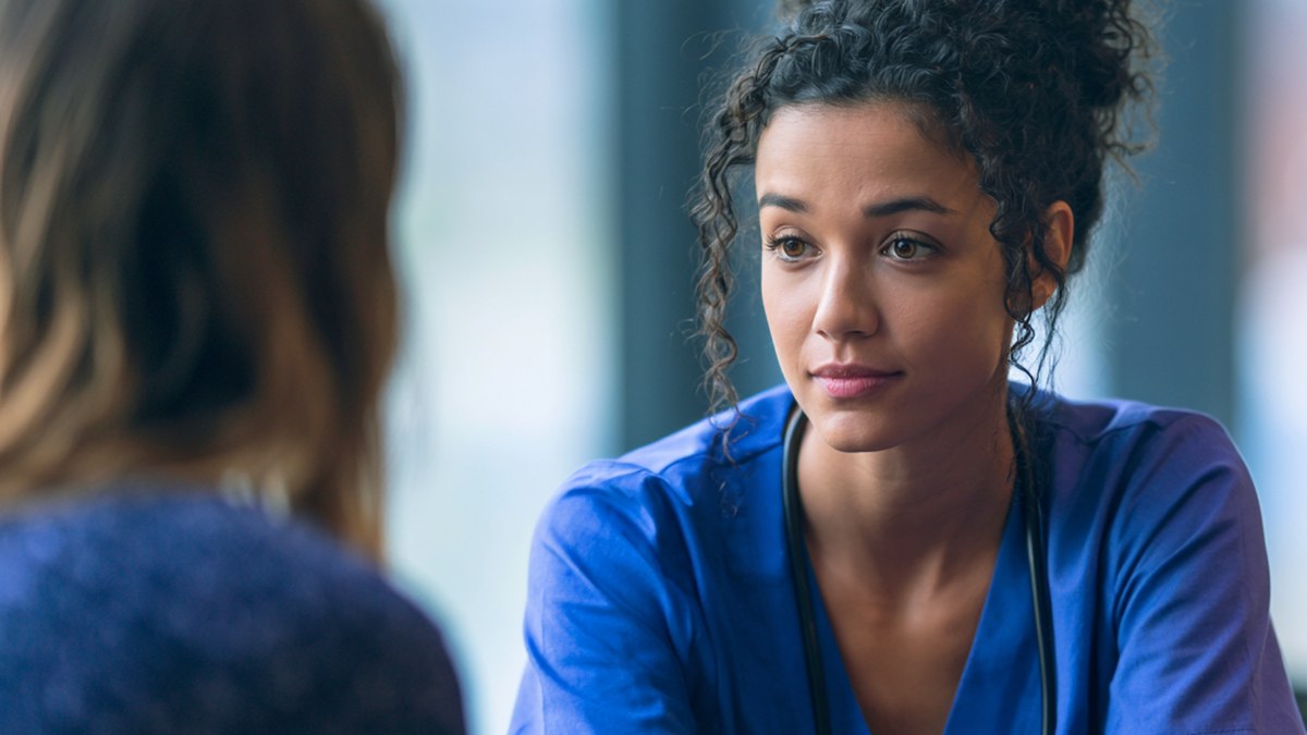 Healthcare worker calmly listening to a distressed patient, illustrating conflict escalation in healthcare settings. Healthcare worker calmly listening to a distressed patient, illustrating conflict escalation in healthcare settings.