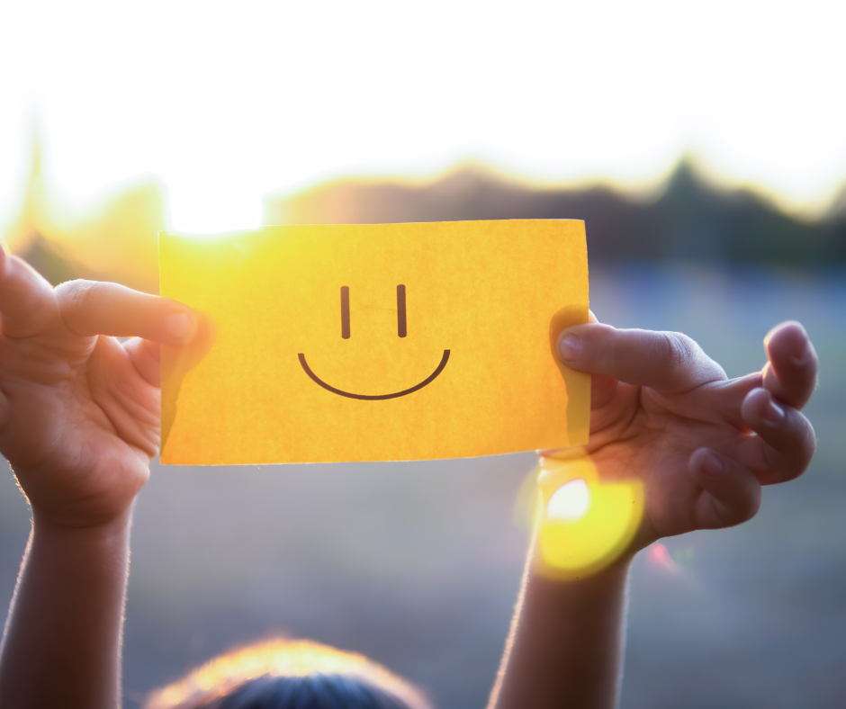Child Holding a Yellow Paper with Smiley Against the Sunlight