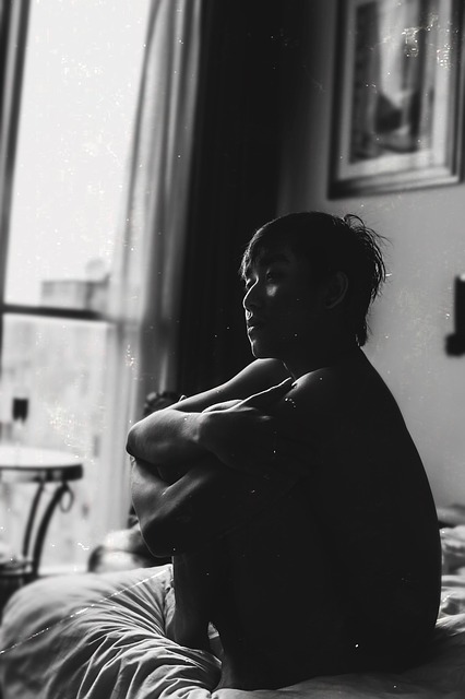 man in bedroom looking alone and isolated