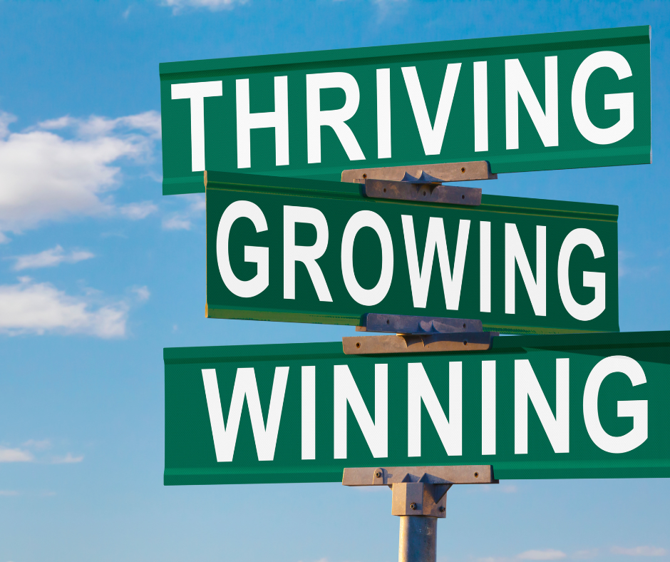 Signposts with the words thriving, growing and winning.