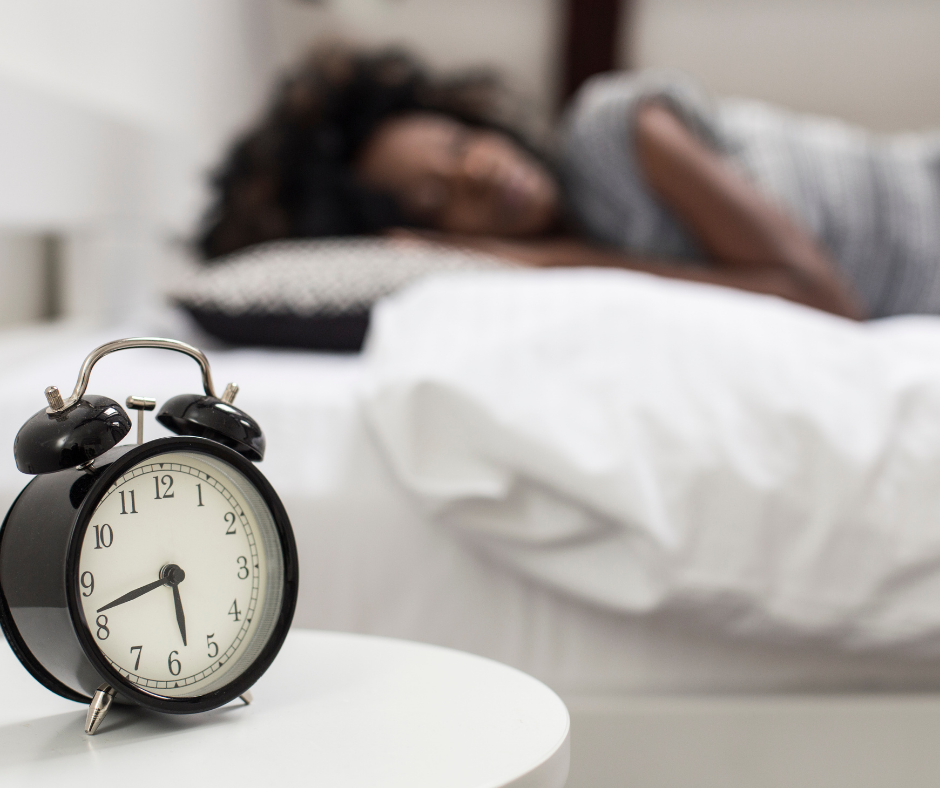 woman sleeping next to an alarm clock