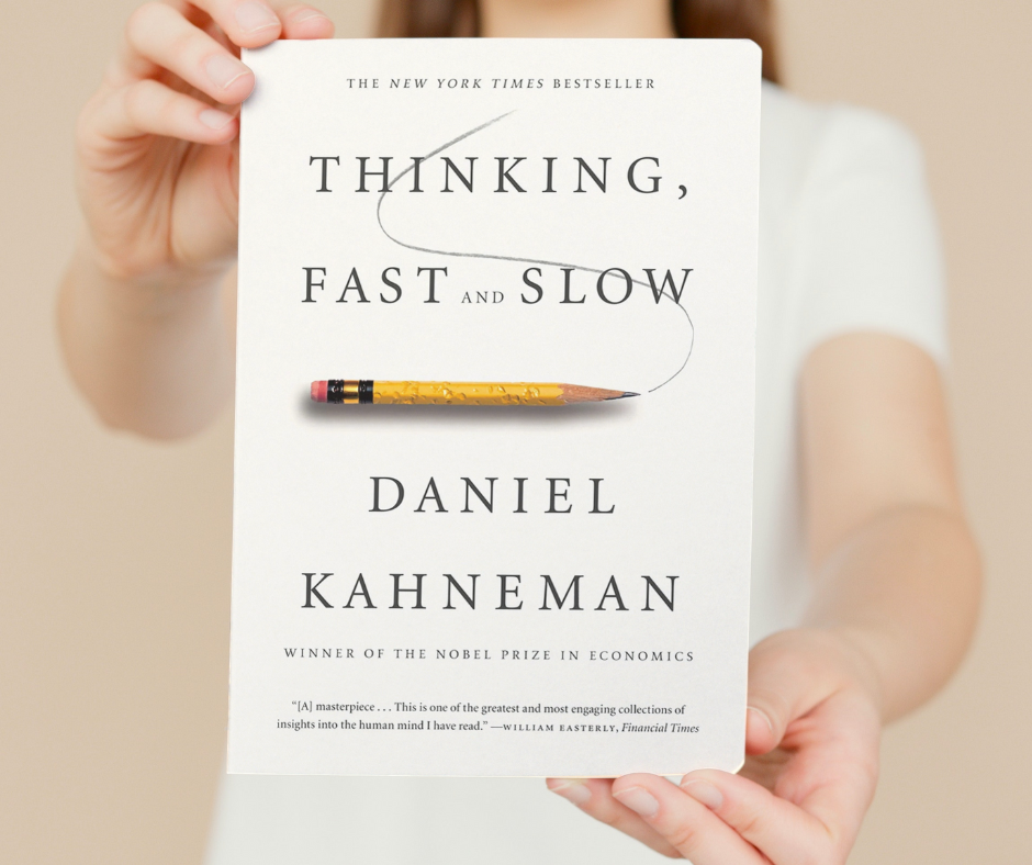 women holding up the book Thinking, Fast and Slow by renowned psychologist and Nobel Prize winner, Daniel Kahneman