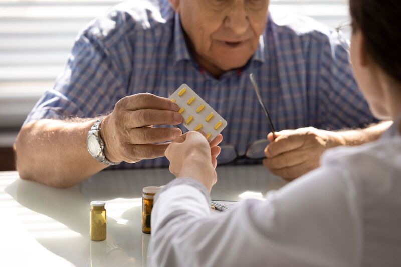 Health professional helping elderly man with his medication