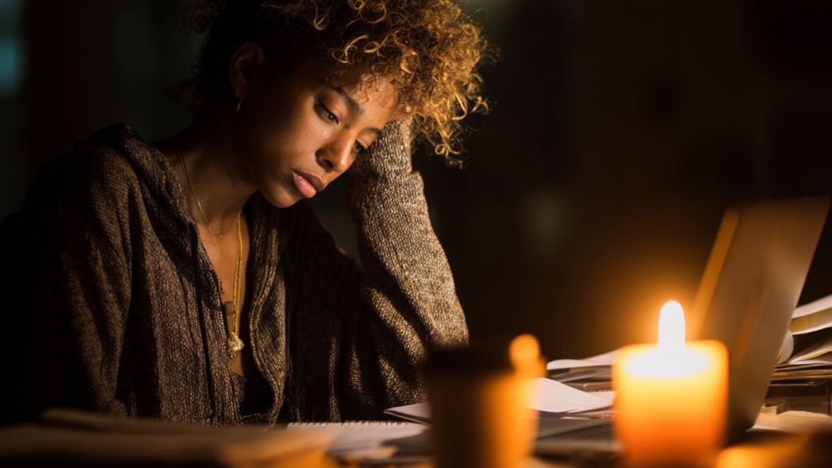 A tired woman working late at night with papers and a laptop, showing signs of work burnout and emotional exhaustion. A tired woman working late at night with papers and a laptop, showing signs of work burnout and emotional exhaustion.