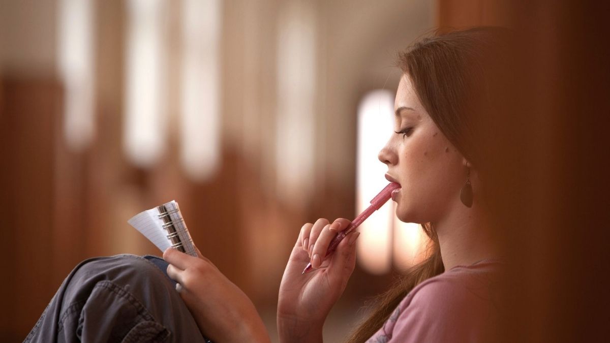 Young woman holding a notebook and pen, illustrating autistic inertia, task switching difficulties, and executive dysfunction. Young woman holding a notebook and pen, illustrating autistic inertia, task switching difficulties, and executive dysfunction.