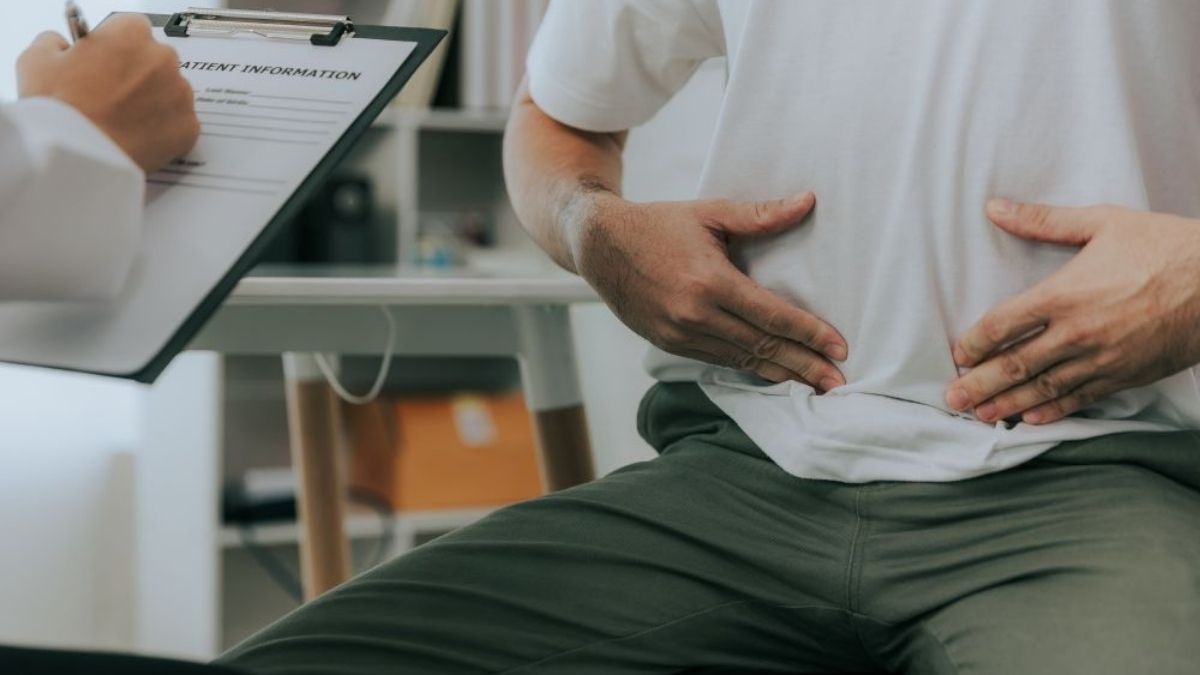 A man holding his stomach during a medical consultation, discussing symptoms linked to food poisoning. A man holding his stomach during a medical consultation, discussing symptoms linked to food poisoning.