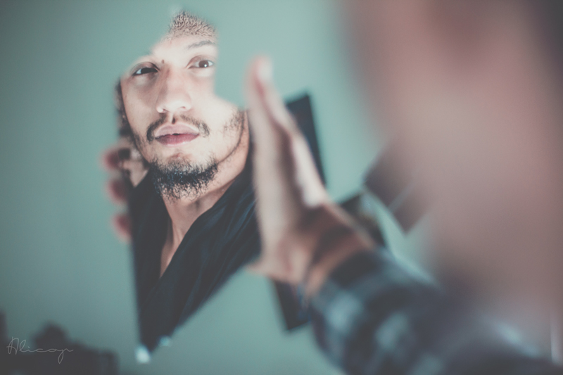 Man looking at reflection in a broken piece of glass.