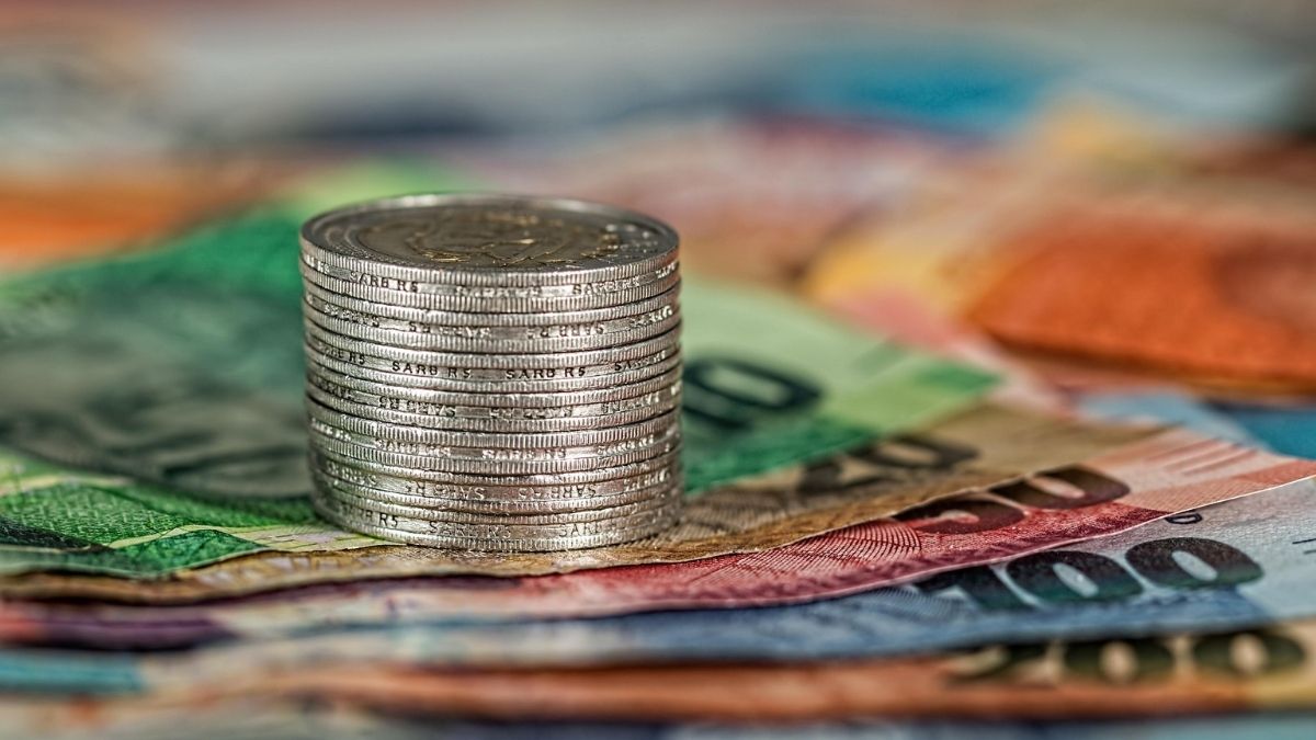 Stack of coins on colorful banknotes, illustrating smart spending, saving money, and building financial well-being in your 20s.