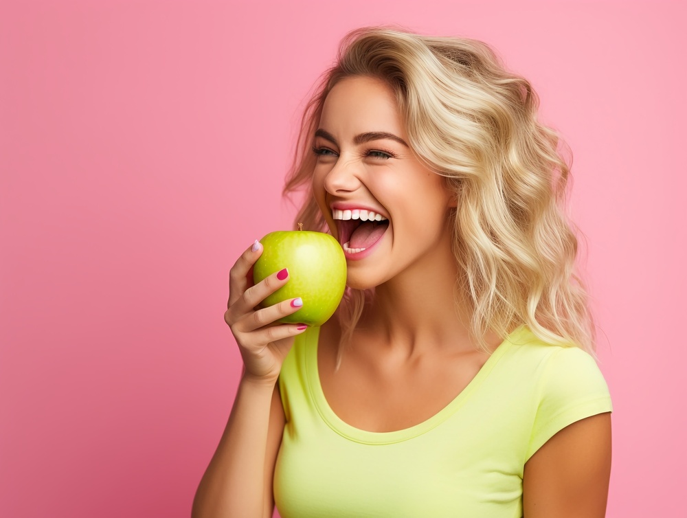 Confident young woman smiling and holding an apple