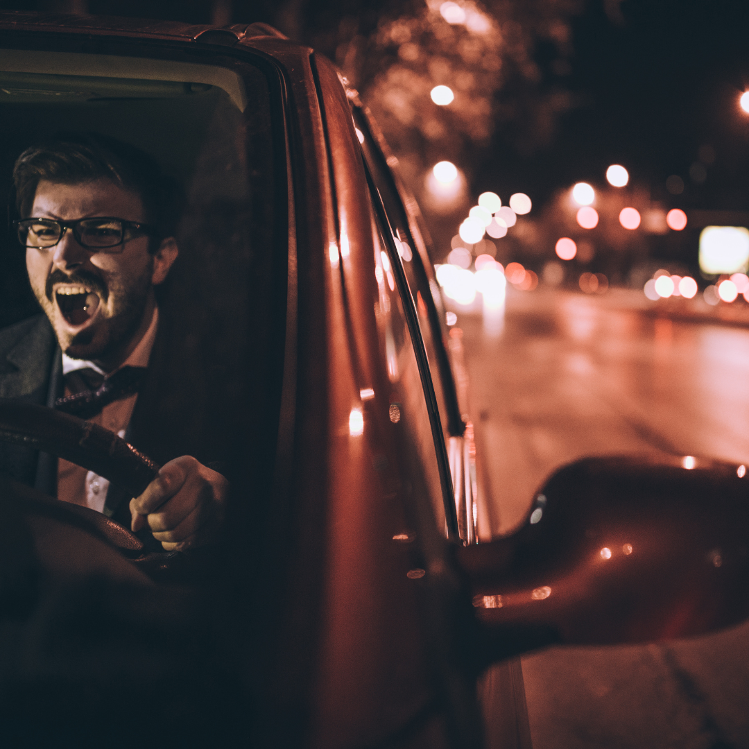 Man driving with an angry expression on his face.